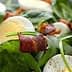 A bowl of salad containing spinach, sliced hard-boiled eggs, and pieces of bacon. - Olive Oil Times
