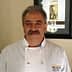A chef wearing a white coat with a UC Davis logo, smiling in a well-lit indoor setting. - Olive Oil Times