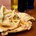 A plate of socca, a type of flatbread, with several bottles of olive oil in the background. - Olive Oil Times