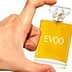 Hand holding a small glass bottle labeled 'EVOO' containing yellow liquid. - Olive Oil Times