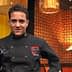 Chef wearing a black culinary uniform with a logo, standing in a restaurant setting. - Olive Oil Times