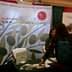 A booth for the North American Olive Oil Association with a banner and a person interacting with staff. - Olive Oil Times