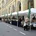 Outdoor market featuring stalls with canopies and various products displayed for sale. - Olive Oil Times
