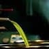 Green olive oil flowing from a spout into a metal container during the extraction process. - Olive Oil Times