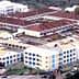 Aerial view of a campus featuring several buildings with red roofs and green spaces. - Olive Oil Times