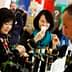 Two women sampling olive oil at a trade show, one holding a tasting cup and the other observing. - Olive Oil Times