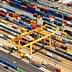 Aerial view of a cargo container terminal with various shipping containers and cranes. - Olive Oil Times