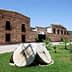Exterior view of an olive oil mill featuring large stone grinding wheels in the foreground. - Olive Oil Times
