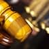 Close-up of a wooden gavel with scales of justice blurred in the background. - Olive Oil Times