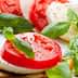 Sliced tomatoes and mozzarella cheese garnished with fresh basil leaves on a plate. - Olive Oil Times