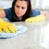 Individual wearing yellow gloves cleaning a countertop with a blue cloth in a bright indoor setting. - Olive Oil Times
