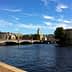 View of a bridge over water in Stockholm with buildings and trees in the background. - Olive Oil Times