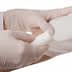 A medical professional in gloves applying a bandage to a patient's arm. - Olive Oil Times