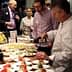 Chef pouring olive oil over a plate of food at a culinary event with attendees observing. - Olive Oil Times