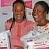 Two women smiling while holding Mother's Delivery Kits in their hands. - Olive Oil Times