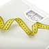 White analog bathroom scale with a measuring tape curled around it. - Olive Oil Times