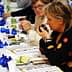 Two women participating in an olive oil tasting event, examining samples at a table. - Olive Oil Times