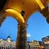 Archway with decorative columns and lanterns, overlooking a city square in Trieste during twilight. - Olive Oil Times