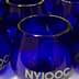 Set of cobalt blue glasses featuring the NYIOOC logo on the front. - Olive Oil Times