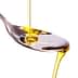 Olive oil being poured from a bottle into a stainless steel spoon. - Olive Oil Times