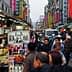 Crowd of people walking through a bustling street market in Taiwan with various stalls and signage. - Olive Oil Times