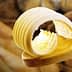 Slices of butter arranged on a wooden spoon with a smooth texture. - Olive Oil Times