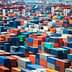 Aerial view of numerous shipping containers stacked in various colors at a port facility. - Olive Oil Times