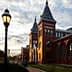 Red brick building with pointed towers and large windows under a cloudy sky. - Olive Oil Times