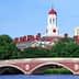 Harvard University building featuring a red dome and clock tower, viewed from across the river. - Olive Oil Times