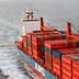 A large container ship with stacked cargo containers navigating through the ocean. - Olive Oil Times
