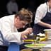 Chef focused on plating a dish during a cooking demonstration on stage. - Olive Oil Times
