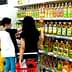 Two individuals shopping for cooking oils on a supermarket shelf filled with various oil bottles. - Olive Oil Times