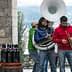 Three musicians performing outdoors with a tuba, trumpet, and other instruments. - Olive Oil Times