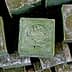 Stack of Aleppo soap bars with a stamped logo on the top bar. - Olive Oil Times