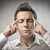Man with closed eyes pressing fingers to his forehead, appearing to concentrate or think deeply. - Olive Oil Times