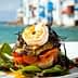 A layered dish featuring shrimp, vegetables, and greens presented on a plate. - Olive Oil Times