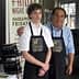 Two individuals wearing store uniforms with the logo 'Golden Bless' standing together in a retail environment. - Olive Oil Times