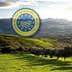 Sicilian landscape featuring rolling hills and olive trees with a geographical indication logo overlay. - Olive Oil Times