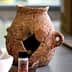 An ancient clay pot with visible cracks and a handle, displaying signs of age and wear. - Olive Oil Times