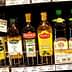 Different brands of olive oil bottles displayed on a supermarket shelf. - Olive Oil Times