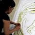 Individual applying olive oil to a large sheet of white paper to create artwork. - Olive Oil Times