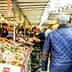 Busy market scene featuring various stalls with fresh produce and shoppers walking through the aisles. - Olive Oil Times