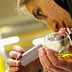 Individual examining olive oil in a glass using a measuring device for analysis. - Olive Oil Times