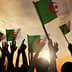 People holding Algerian flags with raised hands against a sunset background. - Olive Oil Times