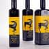 Three bottles of Terra Delyssa organic extra virgin olive oil with a yellow label featuring a black horse design. - Olive Oil Times