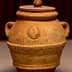 Ceramic pot with a lid, featuring engraved text and decorative patterns on the surface. - Olive Oil Times