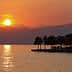 Sunset view over Lake Garda with silhouettes of trees and mountains in the background. - Olive Oil Times