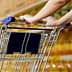 Close-up of a person's hand holding the handle of a shopping cart in a store. - Olive Oil Times