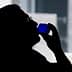 Silhouette of a person holding a blue glass to their lips while drinking. - Olive Oil Times