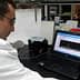 A scientist in a lab coat examining data displayed on a laptop screen in a laboratory setting. - Olive Oil Times